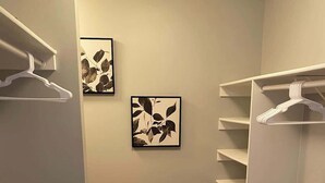A walk-in closet with wooden flooring, grey walls, and white shelving units. - 6BR Downtown | Side-by-Side Townhomes | 2 Garages (Indianapolis)
