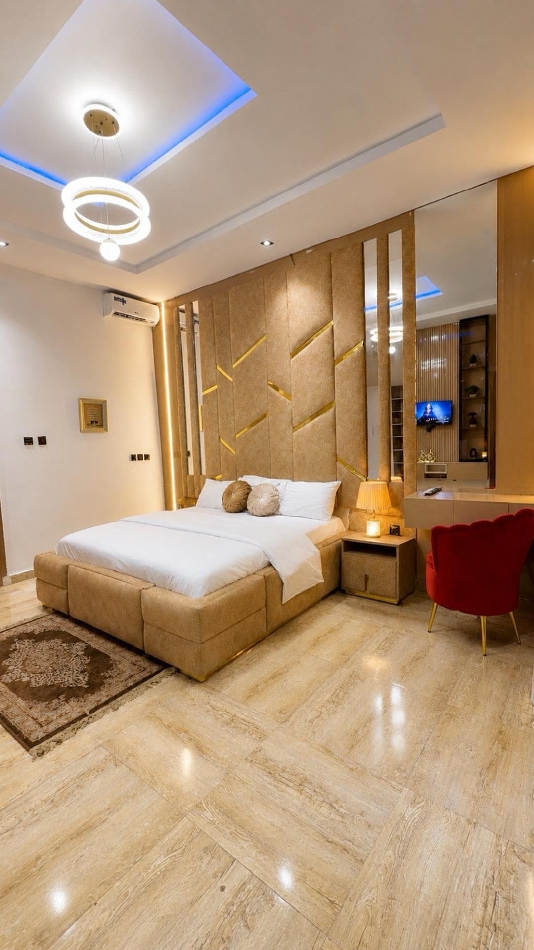 A modern bedroom with a bed, bedside table, lamp, and a red chair.