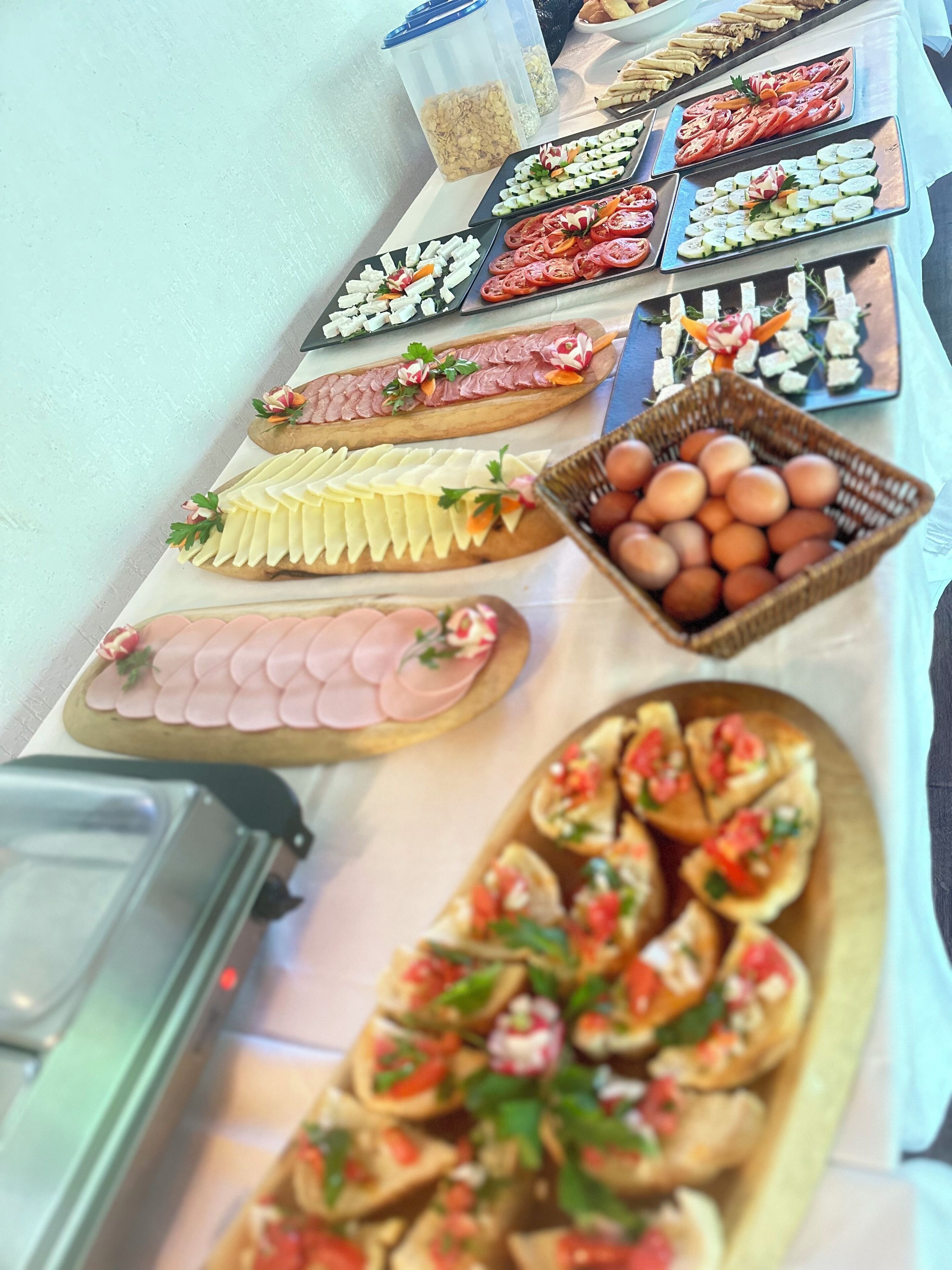 A buffet table with various food items including sliced meats, cheeses, and vegetables.