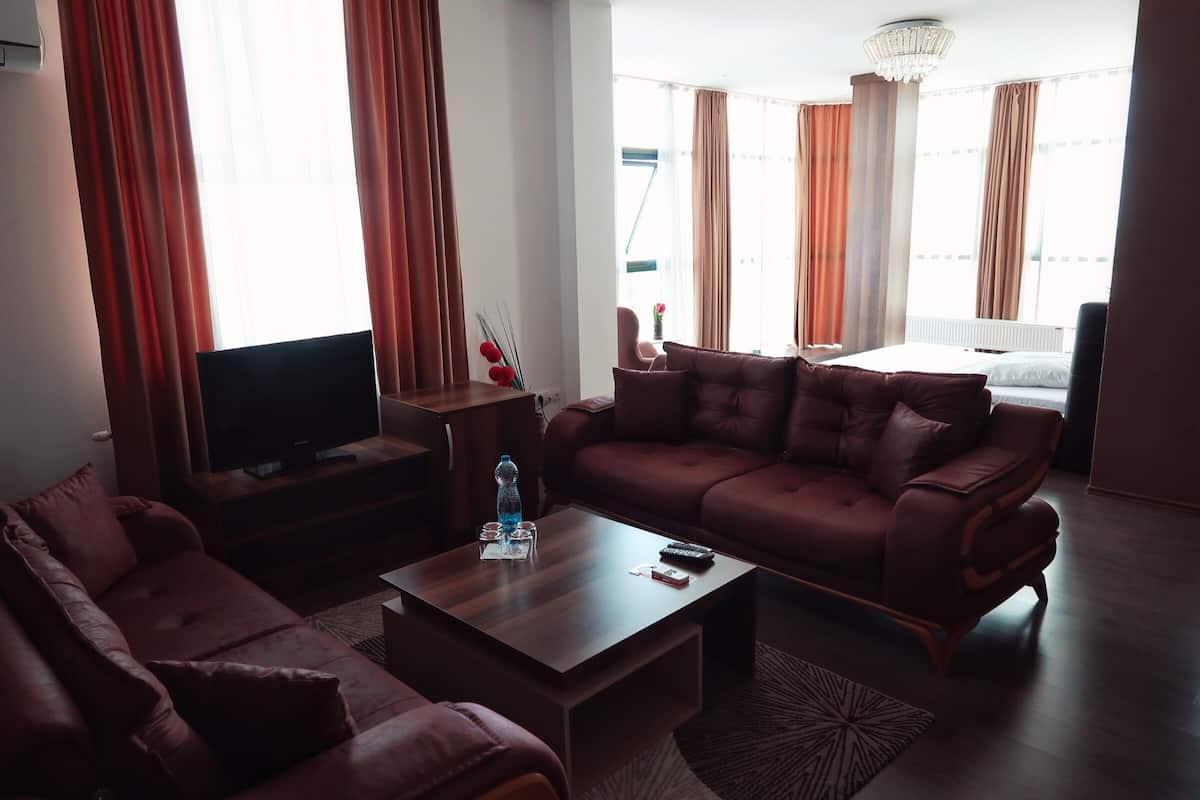 A modern living room with a large flat-screen TV, a brown leather sofa, and a wooden coffee table.