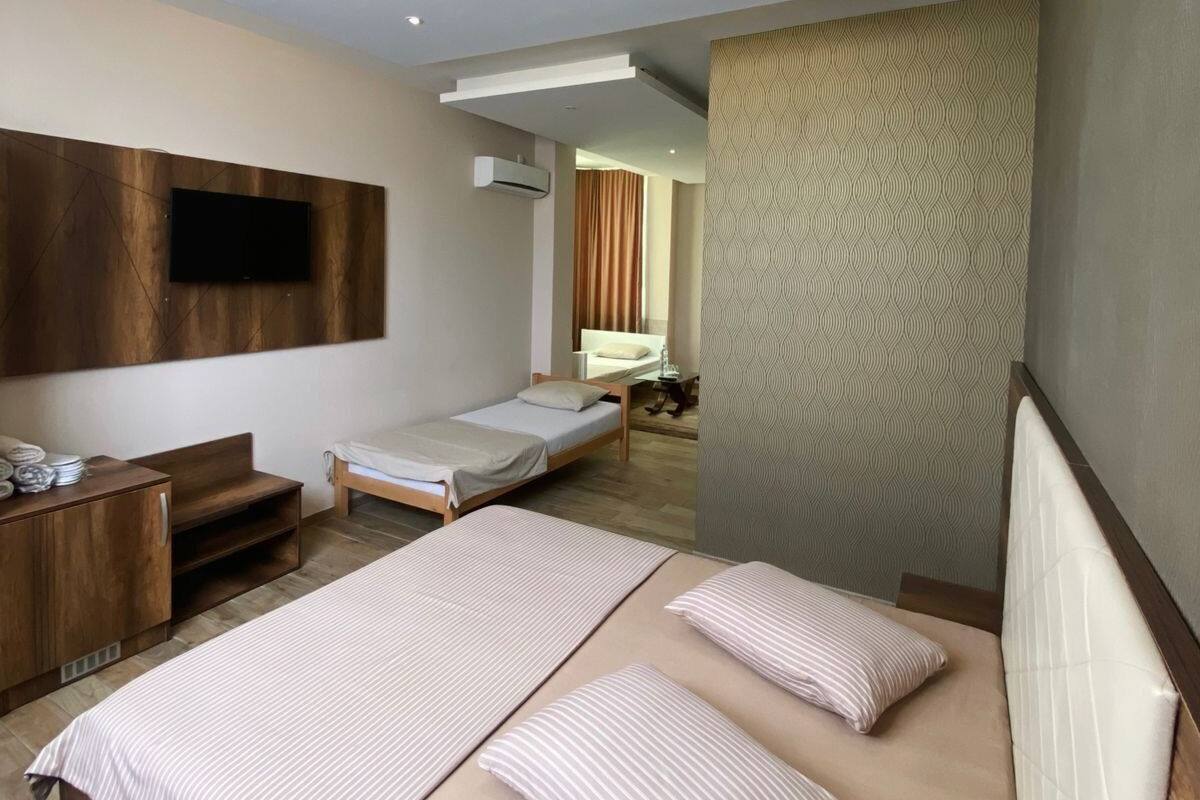 A modern hotel room with a large bed, a wooden desk, a flat-screen TV mounted on the wall, and a patterned wall.