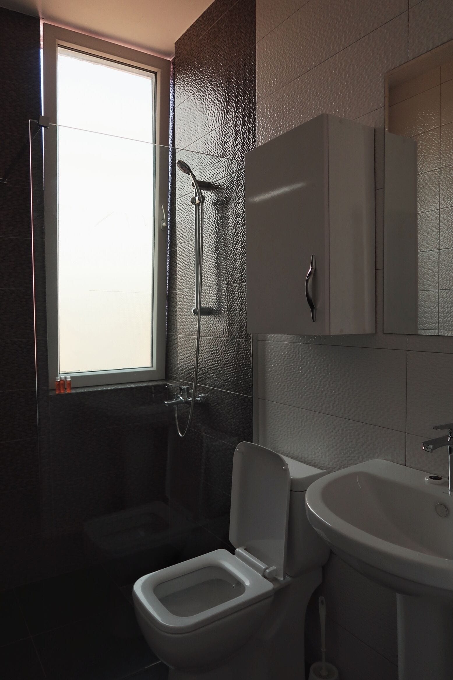 A bathroom with a shower, toilet, and sink.