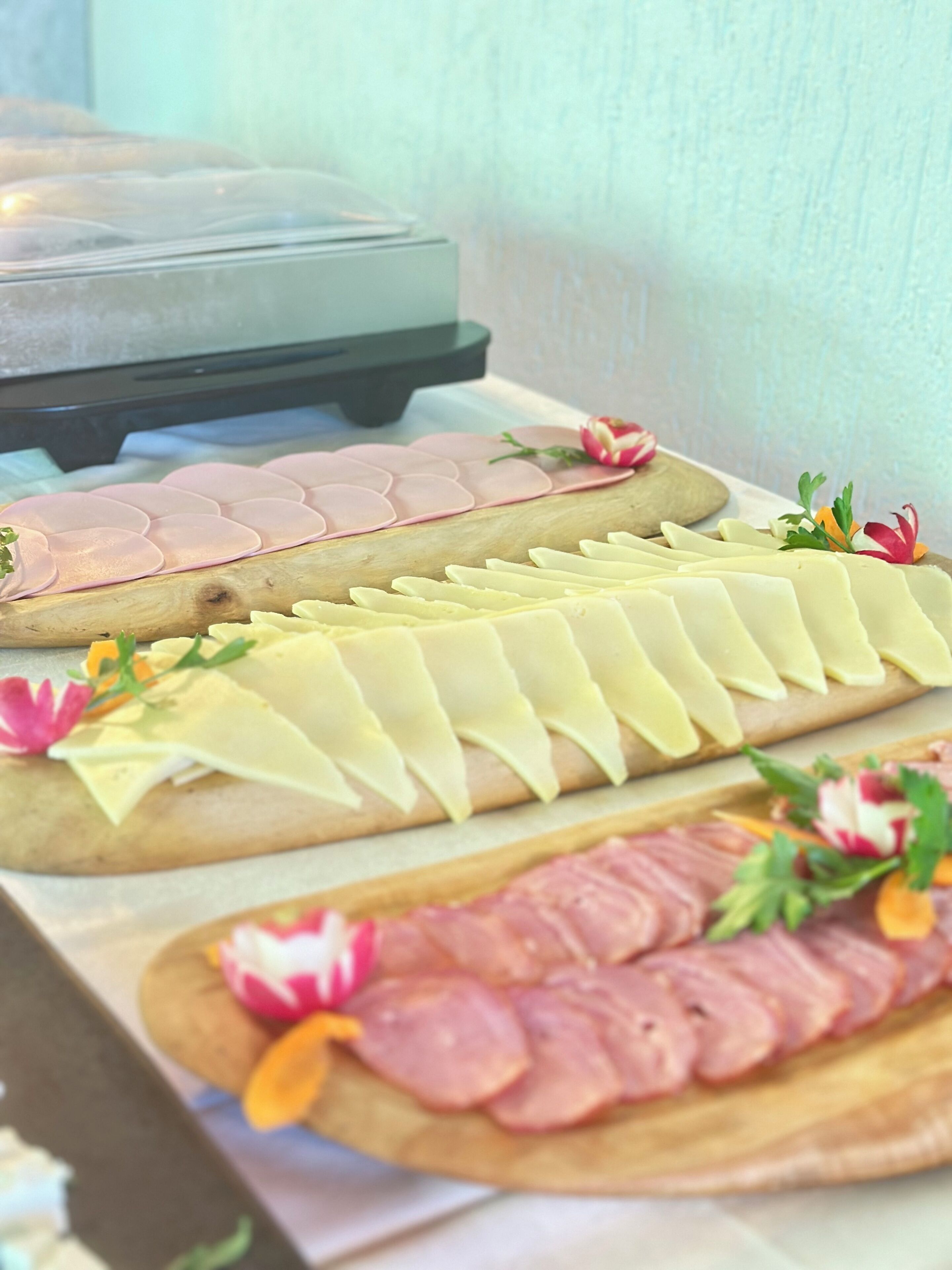 A buffet table with various food items including sliced meats and cheeses.
