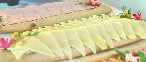 A buffet table with various food items including sliced meats and cheeses.