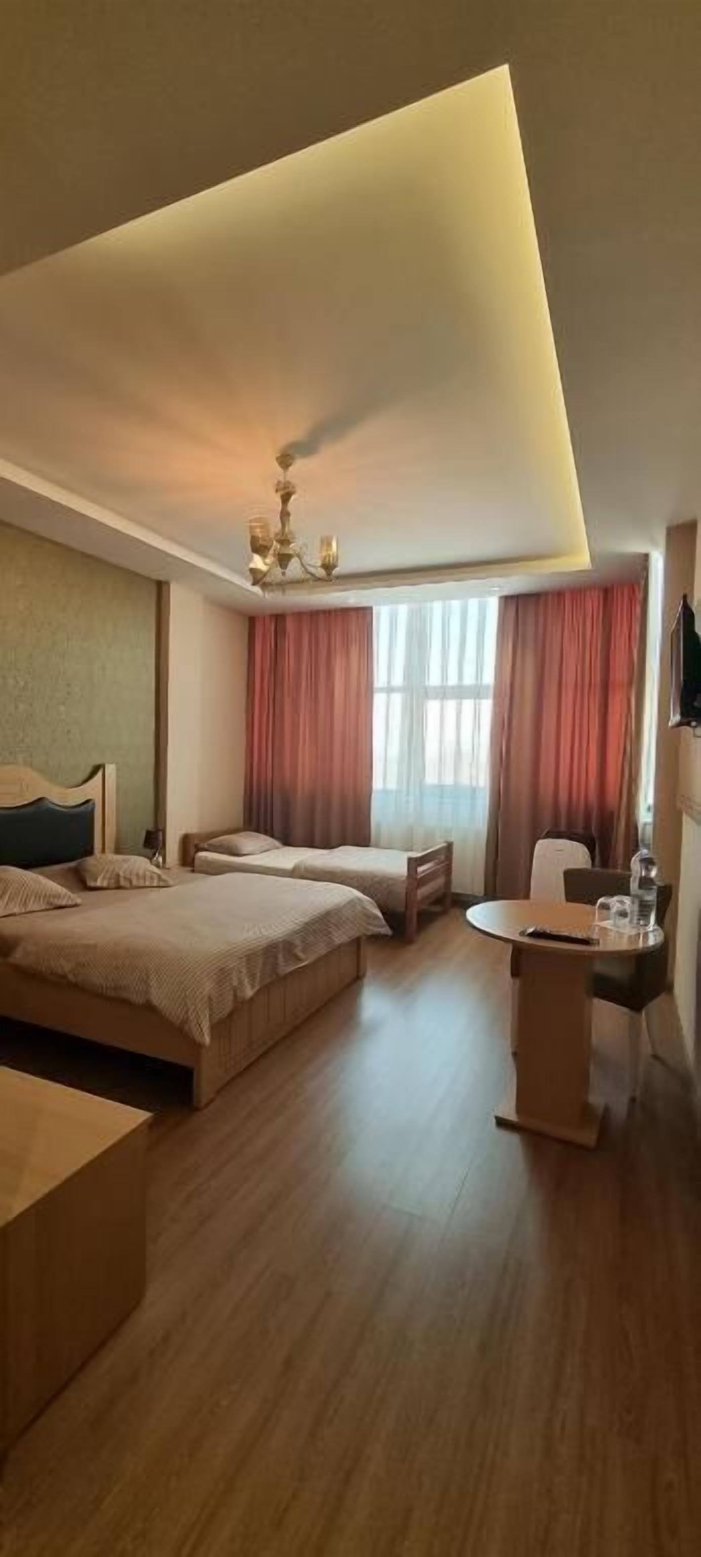 Een hotelkamer met een groot bed, een kleiner bed, een bureau en een stoel.