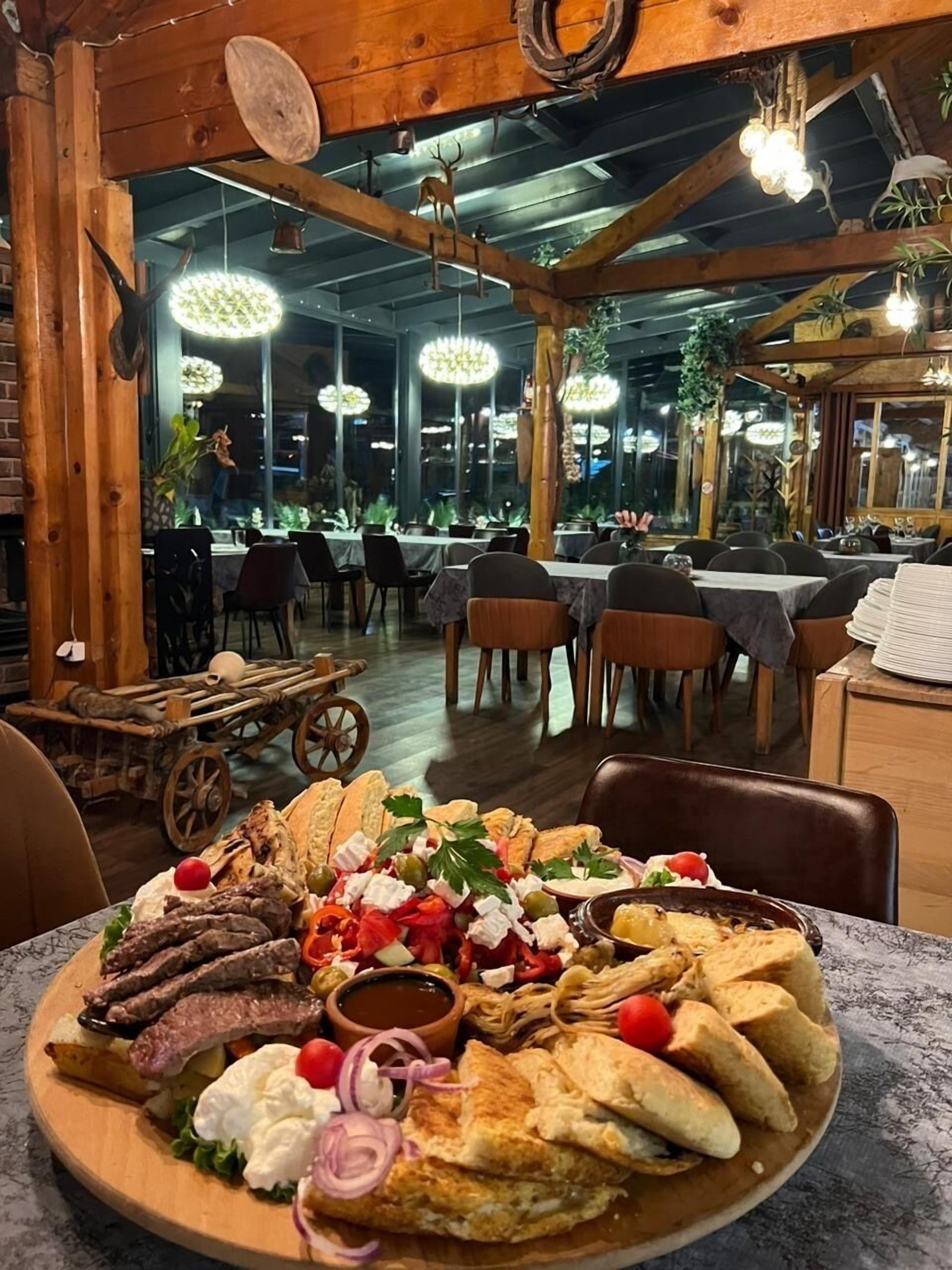 A restaurant with a rustic interior, wooden beams, and a variety of dishes on a large platter.