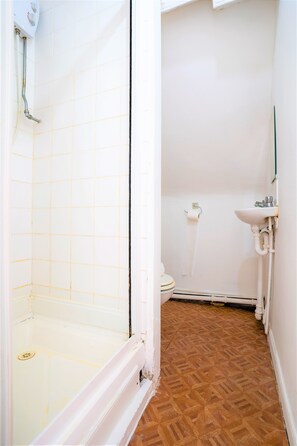 Een badkamer met douche, toilet en wastafel.