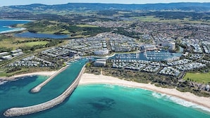 An aerial view of a coastal residential area with a marina, sandy beaches, and a large body of water.