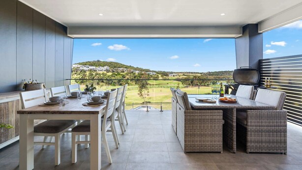 A balcony with a dining table, chairs, and a grill.