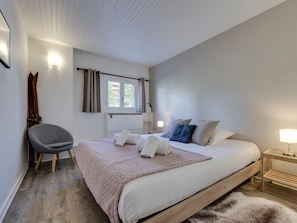 A bedroom with a bed, a chair, a window with curtains, a lamp, and a fur rug. - Tignes le Lac 5-room spacious duplex, quiet central area, Wi-Fi included (Tignes)
