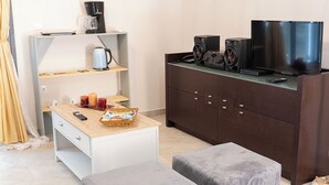 A modern room with a wooden desk, a coffee maker, a television, and a cabinet. - Charming 1-bedroom apartment in delightful Chios and traditional Kampos area.  (Chios)