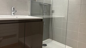 Een moderne badkamer met een douche, wastafel en spiegel.