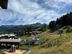 Una stazione sciistica con una seggiovia, edifici e montagne sullo sfondo.