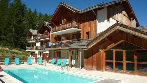 A wooden chalet with a pool and outdoor seating. - Modern 2-room apartment for 6 people with pool, sauna, hammam, wifi and pets allowed (Les Orres)