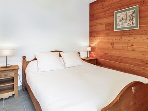 Un lit bien fait, avec du linge de lit blanc, une tête de lit en bois et deux lampes de chevet.