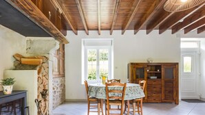 A dining area with a table, chairs, a fireplace, and a stone wall. - Restored 19th Century Semi-detached House in Normandy (Saint-Joseph (Manche))