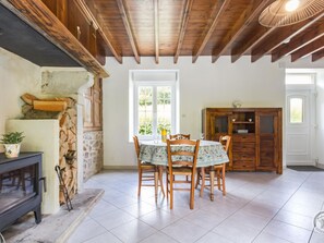 Un comedor con una mesa, sillas, una chimenea y una pared de piedra.