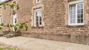A stone building with multiple windows, a small garden area with gravel, and a visible door. - Restored 19th Century Semi-detached House in Normandy (Saint-Joseph (Manche))