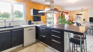 A modern kitchen with black and white cabinetry, a stainless steel range hood, and a large island with bar stools. - Spacious house with enclosed garden in Yvetot-Bocage (Yvetot-Bocage)