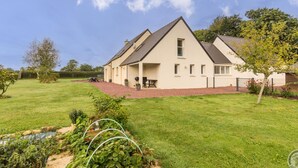 A two-story house with a sloped roof, a covered patio, and a well-maintained lawn. - Spacious house with enclosed garden in Yvetot-Bocage (Yvetot-Bocage)