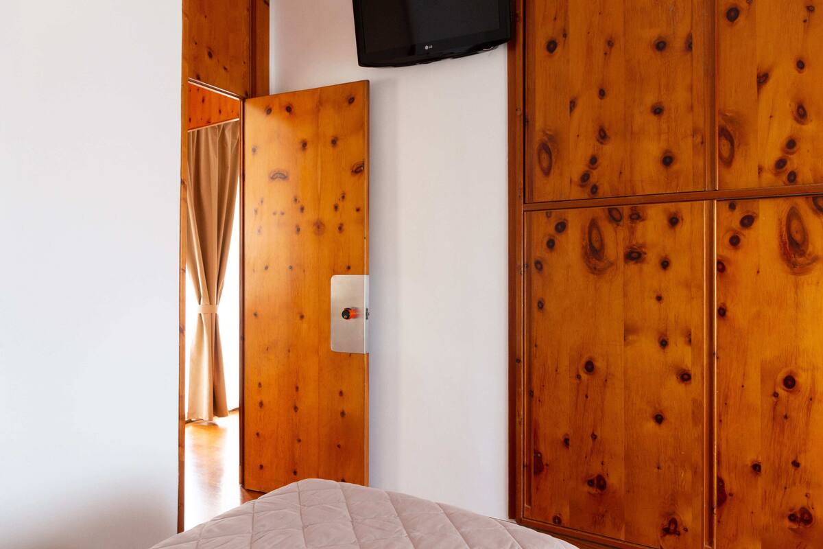Een slaapkamer met houten kasten, een bed en een televisie aan de muur.