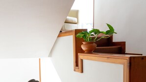 Eine Frau geht eine Holztreppe hinauf, auf der Zwischenebene steht ein Blumentopf.