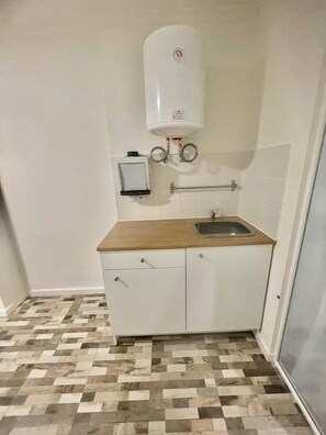 Kitchen area with a stainless steel sink, white countertop, and cabinetry.