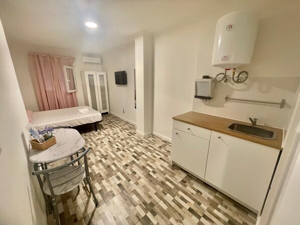 Cozy retreat with a bed, kitchenette, shower, and toilet.