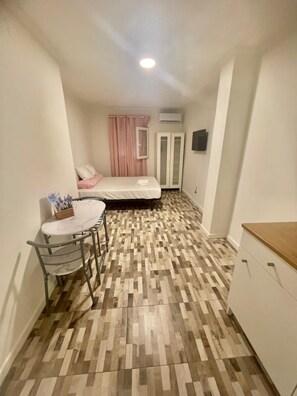 Cozy retreat with a small dining table, comfortable bed, and ample storage in a compact room.