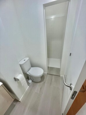 Bathroom features a white toilet and sink, with light-colored tiles covering the floor.
