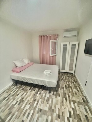 Cozy retreat with a single bed, wardrobe, and flat-screen TV.