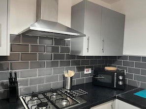 Una cocina moderna con gabinetes grises, una estufa a gas, horno empotrado y microondas.