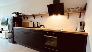 Una cucina moderna con mobili neri, un piano di lavoro in legno, forno integrato e cappa aspirante nera.