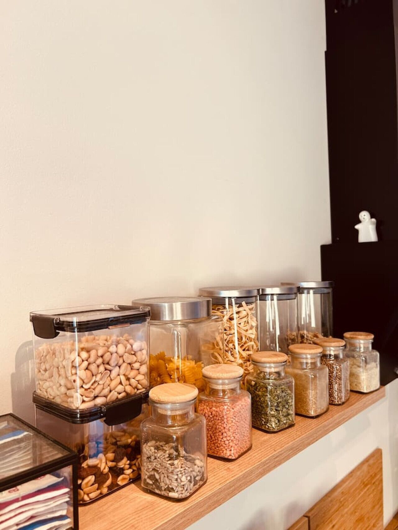 Una tauletta de cuina amb diversos recipients d'emmagatzematge d'aliments, incloent envasos de vidre i un recipient de plàstic.