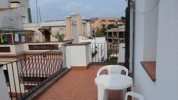 A small outdoor patio with a white table and chairs, a metal railing, and a view of neighboring buildings. - Hotel Caleta  (Lloret de Mar)