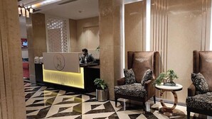 A hotel lobby with a reception desk, patterned chairs, a patterned floor, and a large wall with vertical panels. - Jb innovations (Lucknow)