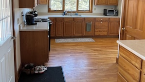 A kitchen with wooden cabinets, a microwave, a sink, and a window. - Quiet Country 2 Bedroom Home Near Bellows Falls & Walpole — Easy I-91 Access (Westminster)