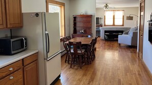 A spacious kitchen with wooden cabinets, a refrigerator, and a dining table with chairs. - Quiet Country 2 Bedroom Home Near Bellows Falls & Walpole — Easy I-91 Access (Westminster)