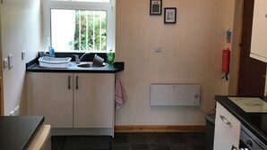 A compact kitchen with a window, a built-in oven, and a black tiled floor.