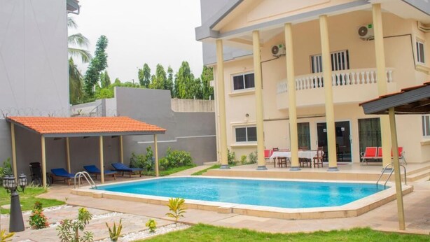 A two-story building with a swimming pool, outdoor seating, and a covered patio area.