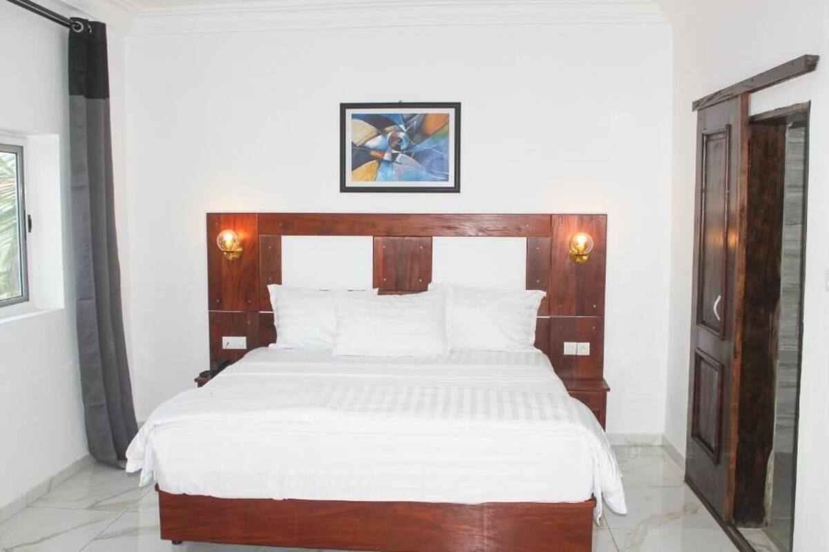 A neatly made bed with a wooden headboard and two wall-mounted light fixtures.