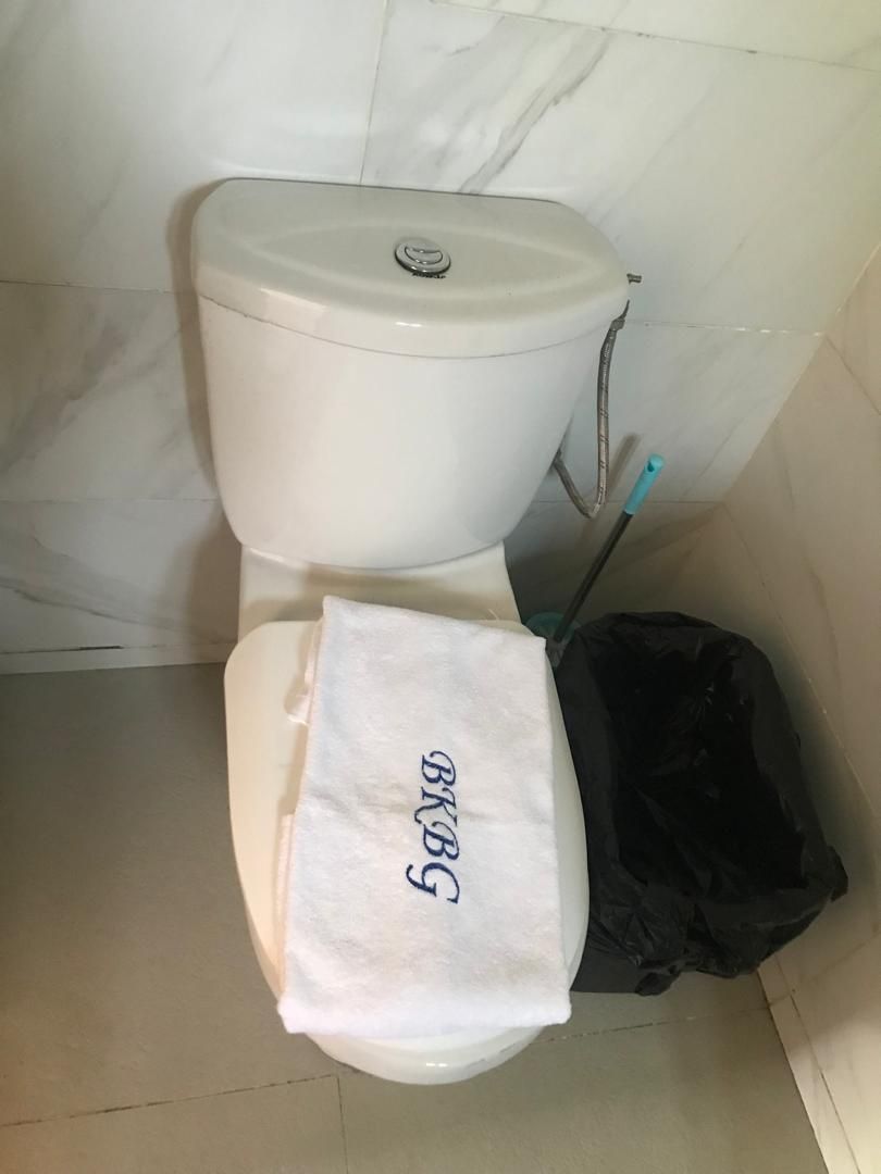 Un inodoro con un asiento blanco y una bolsa negra a su lado.