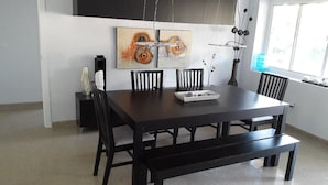 A dining area with a dark wooden table, six chairs, and a painting above.