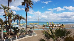 A beach resort with palm trees, lounge chairs, and umbrellas.