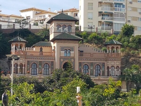 A building with multiple towers and arched windows, surrounded by greenery.