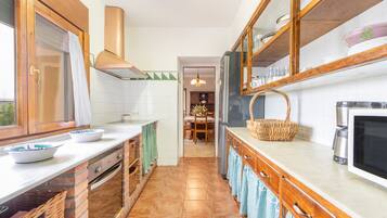Eine Küche mit Ziegelrückwand, Holzschränken, einem Edelstahlkühlschrank und einer Mikrowelle.