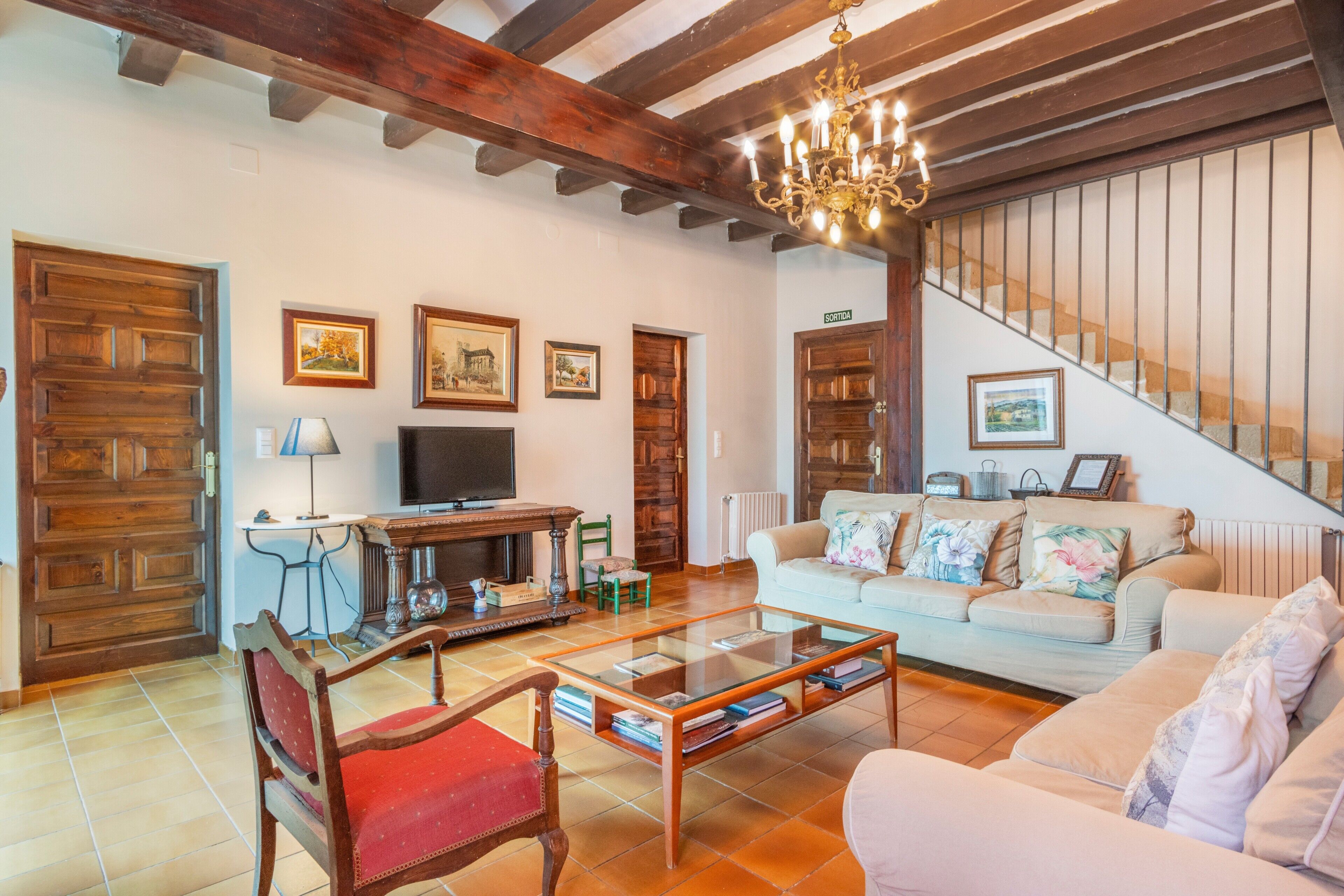 A living room with a sofa, a coffee table, a television, and a staircase.