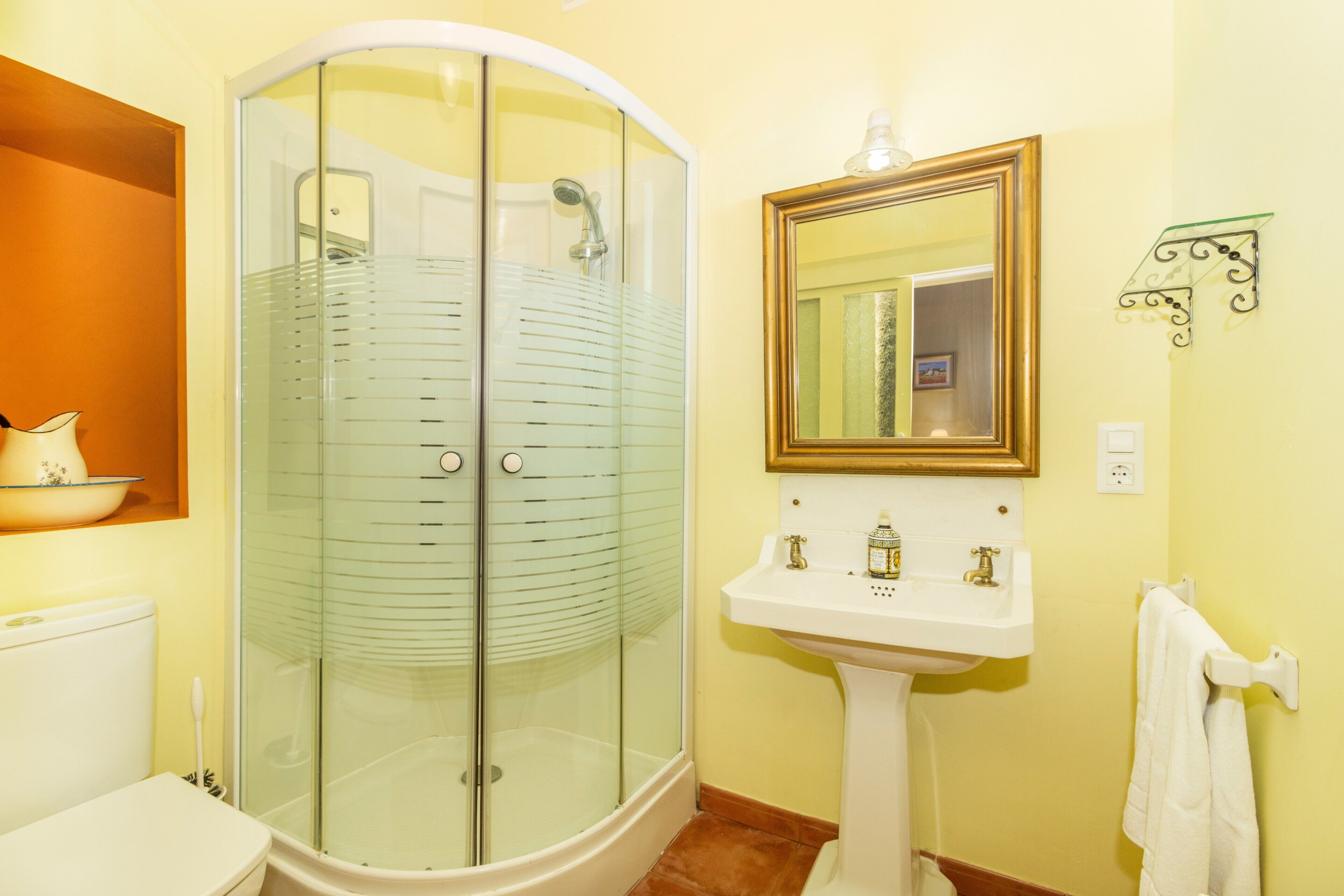 A bathroom with a glass shower enclosure, a white sink, and a mirror.