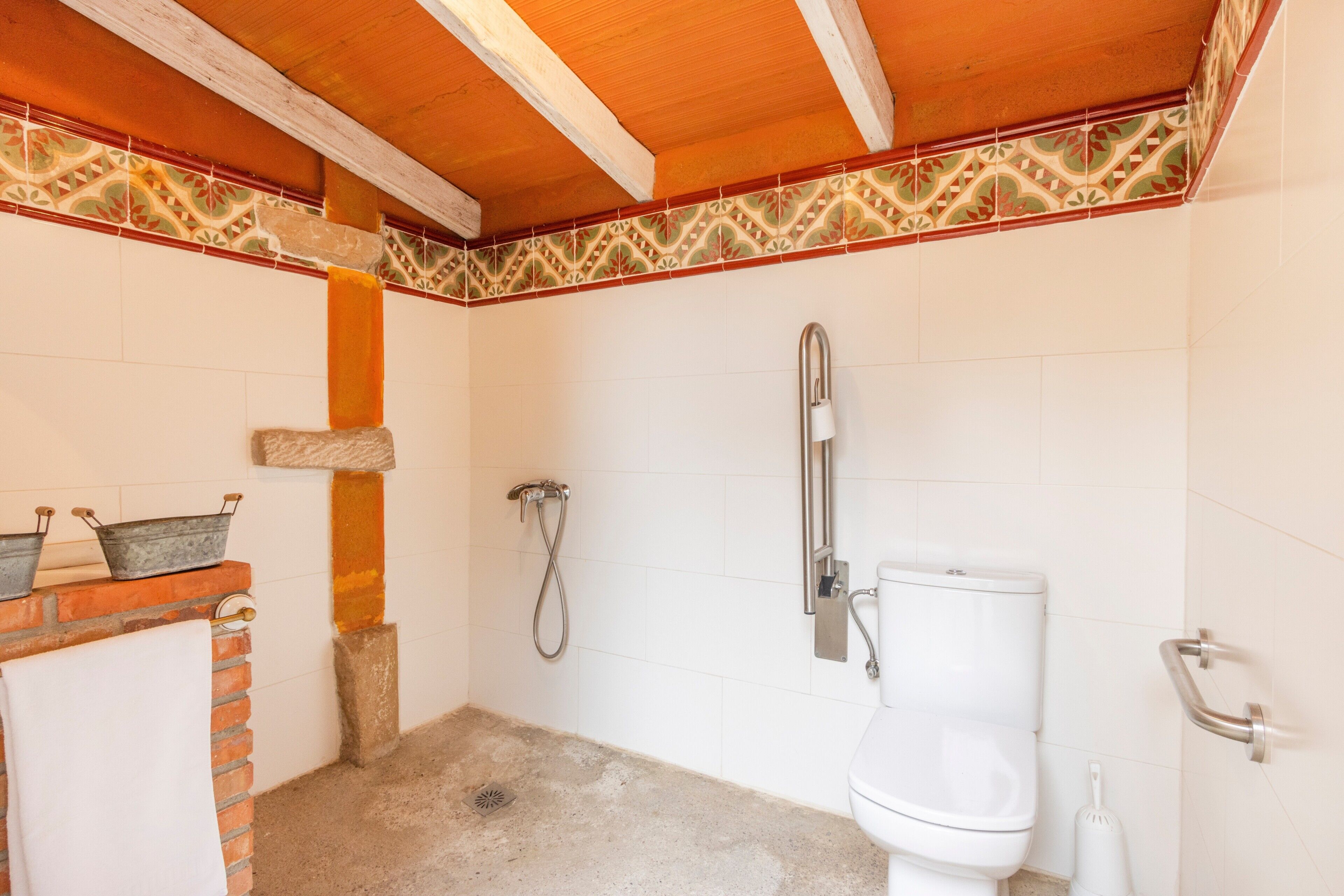 Ein Badezimmer mit Dusche, Toilette und einer mit Dekorleisten versehenen Fliesenwand.