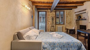 A bedroom with a bed, a sofa, a desk, and a fireplace. - Apartment 'Maison Le Chic' with Wi-Fi (Bergamo)